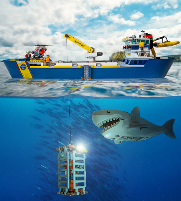 Legoista tehty sukelluskuvaaja kuvaa pinnan alla haukea, taustalla kalaparvi,pinnalla odottaa sukellustukialus.